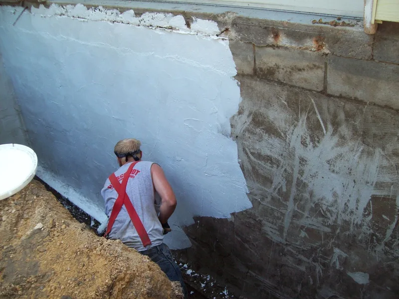 Applying primer to waterproof block wall.